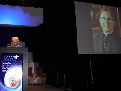 The assembly thanks Archbishop J. Peter Sartain by phone at the closing banquet